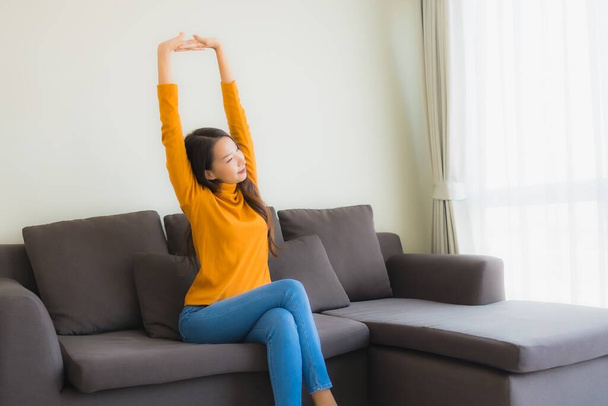 Portrét mladá asijka šťastný relax úsměv na pohovce s polštářem v obývacím pokoji interiér - Fotografie, Obrázek