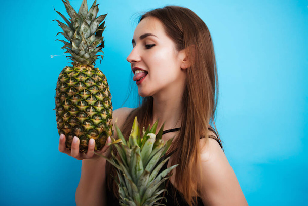Portrait of young woman in swimsuit with pineapple on blue background. Summer season - Foto, Bild