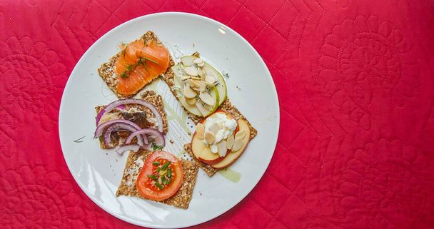 Smrrebrd ist ein traditionelles skandinavisches Sandwich mit offenem Gesicht, das normalerweise aus einem Stück Roggen-Butterbrot (Rugbrd) besteht, einem dichten, dunkelbraunen Brot, das mit handelsüblichem oder hausgemachtem Aufschnitt, Fleisch- oder Fischstücken, Käse oder Brotaufstrichen belegt ist. - Foto, Bild