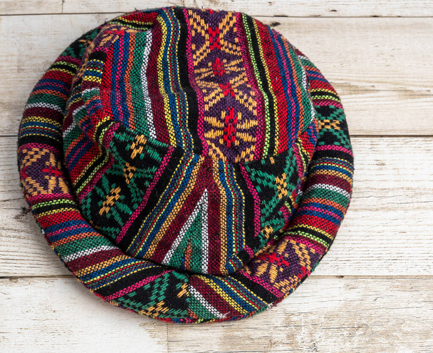 Chapéu multicolorido, padrão de seda, tapetes no chão de madeira. Foto
 - Foto, Imagem