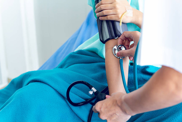 Médicos femeninos examen médico medición de presión de pacientes femeninos en cama de hospital
. - Foto, Imagen