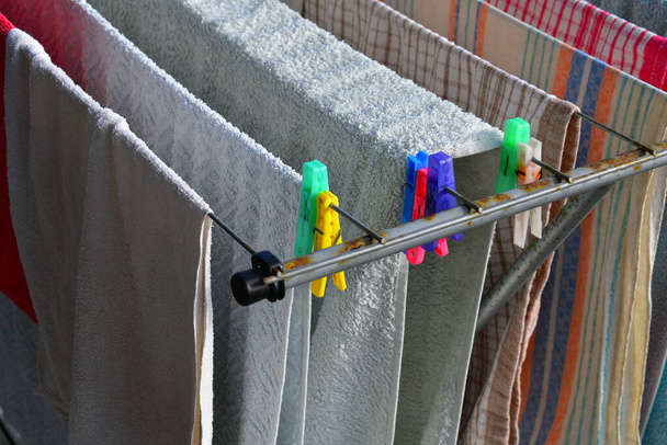 Uitzicht op natte handdoeken drogen op waslijn op zonnige dag - Foto, afbeelding