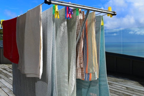 Uitzicht op natte handdoeken drogen op waslijn op zonnige dag - Foto, afbeelding