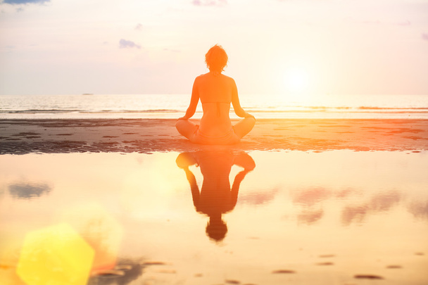 Yoga vrouw in lotus pose zittend op het strand - Foto, afbeelding