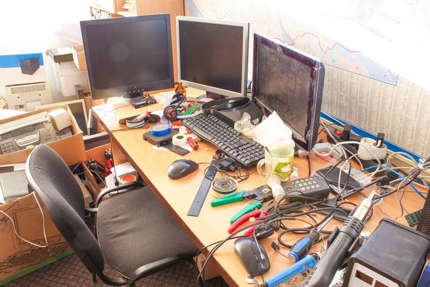 Un escritorio desordenado con pilas de archivos y otros documentos, todo tipo de suministros de oficina y parte de un teclado y PC
. - Foto, Imagen