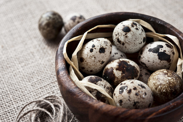 Quail eggs in wooden bowl on sack background - Foto, Imagem