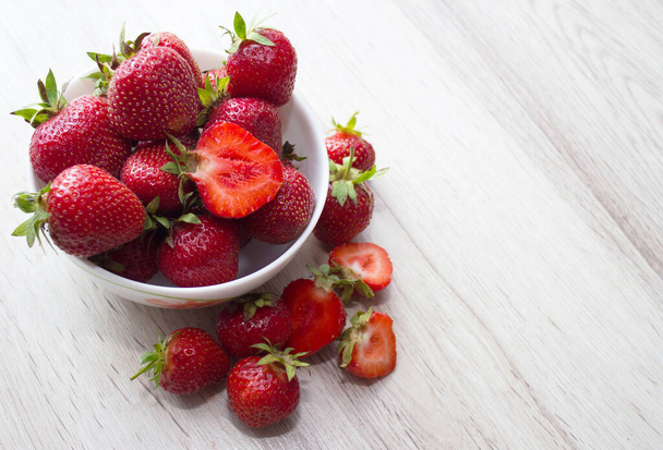Heap of fresh strawberries in ceramic bowl on rustic white wooden background. - Foto, imagen