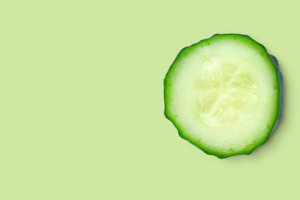 One slice closeup of fresh organic cucumber isolated on a green background. The concept of freshness, juiciness,diet. Top view with copy space. - Foto, imagen