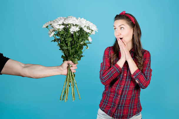 Une paysanne en chemise à carreaux rouge est agréablement surprise, la main d'un homme lui tend un bouquet de fleurs - des chrysanthèmes blancs - Photo, image
