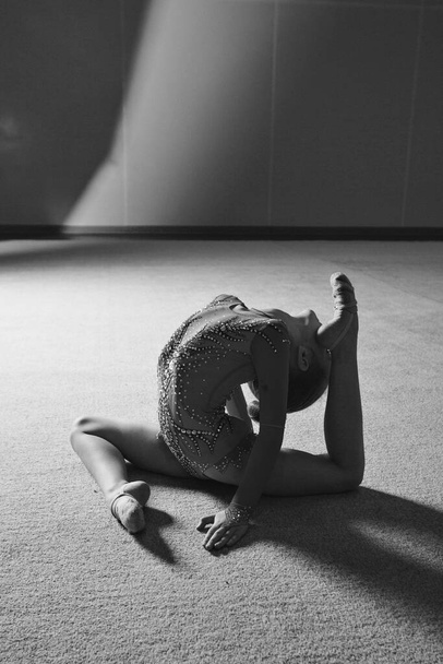 A girl in a tracksuit does a stretch. Gymnast goes in for sports. Healthy lifestyle concept, sports uniforms, world Cup, gym, specialized clothing, uniforms - Photo, Image