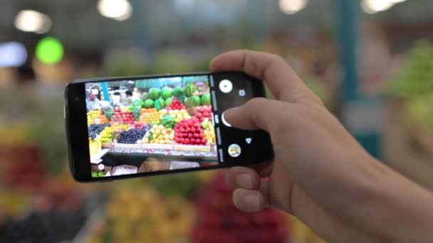Muž fotí ovoce a zeleninu na místním trhu u telefonu - Záběry, video
