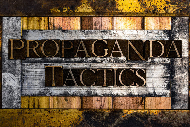 Propaganda Tactics text formed with real authentic typeset letters on vintage textured silver grunge copper and gold background - Photo, Image