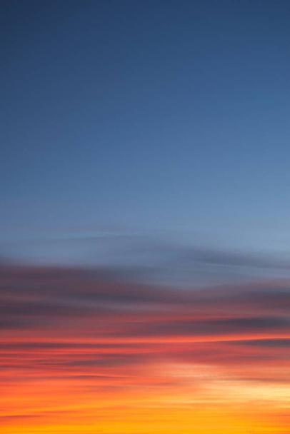 Intenzív, ragyogó narancssárga cirrus felhők hajnalban a mély kék ég ellen. - Fotó, kép