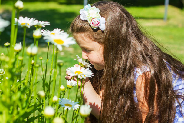 Het kleine meisje ademt de geur van bloemen, mooi meisje met witte bloemen - Foto, afbeelding