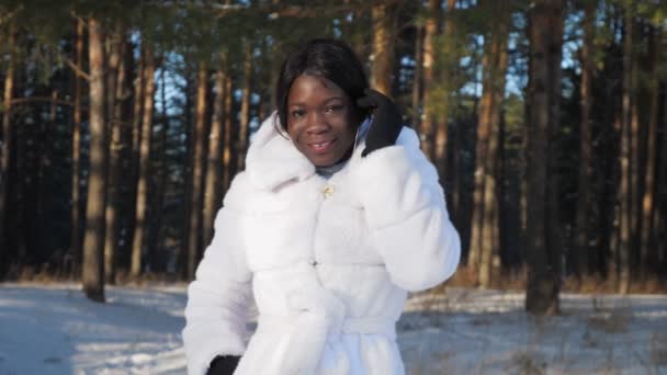negro chica poses cogidas de la mano en bolsillos contra snowy park - Metraje, vídeo