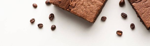 top view of delicious brownie pieces with coffee beans on white background, panoramic shot - Fotó, kép
