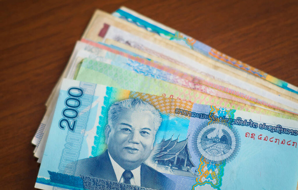 Laoszi valuta. Kétezer kiló, Kaysone Phomvihane elnök képével, egy halom ázsiai bankjegy tetején.. - Fotó, kép