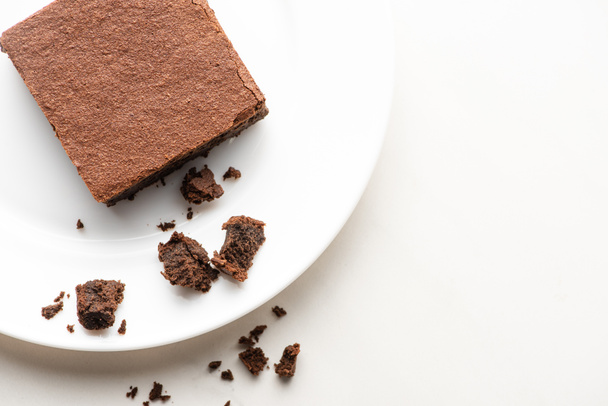 top view of delicious brownie piece on plate on white background - Zdjęcie, obraz