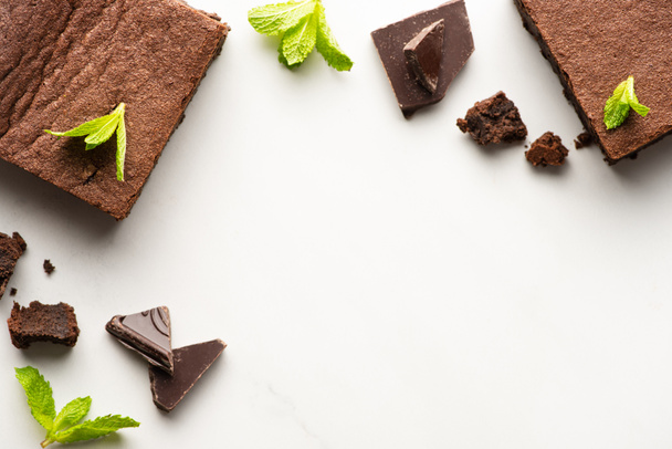 top view of delicious brownie pieces with mint and chocolate on white background - Foto, immagini