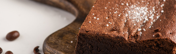 Nahaufnahme von köstlichem Brownie-Stück auf Holzschneidebrett mit Kaffeebohnen auf weißem Hintergrund, Panoramaaufnahme - Foto, Bild