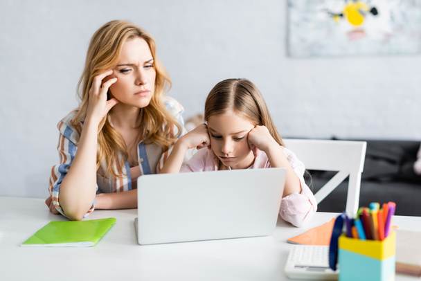 Szelektív fókusz a töprengő anya és gyerek nézi laptop alatt online oktatás otthon  - Fotó, kép