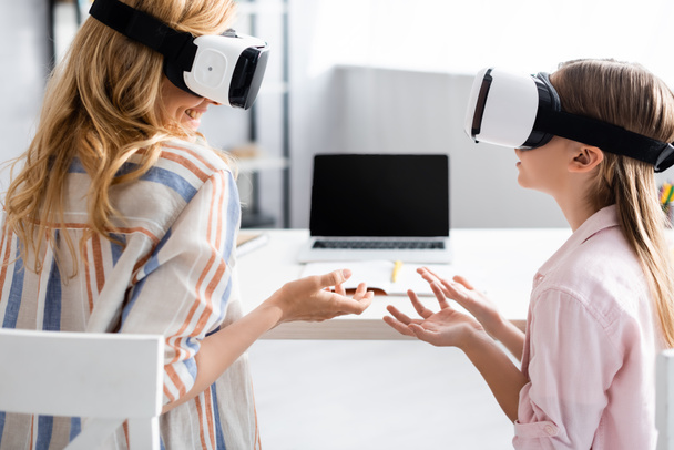 Smiling woman using vr headsets with daughter at home  - Φωτογραφία, εικόνα