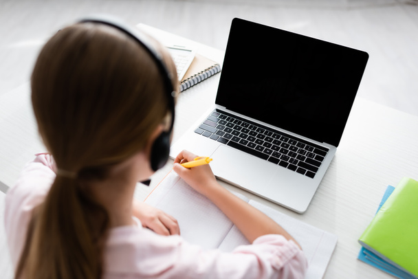 Vista aérea del niño en la escritura de auriculares en el portátil durante la educación en línea en el hogar
  - Foto, imagen