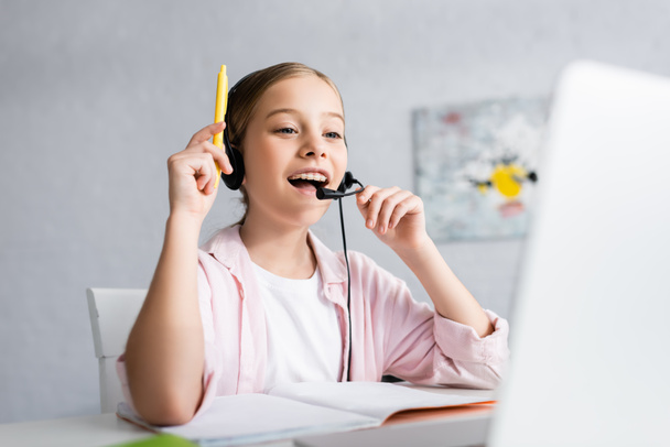 Selektywne skupienie pozytywnego dziecka w słuchawkach mając pomysł podczas edukacji online w domu  - Zdjęcie, obraz