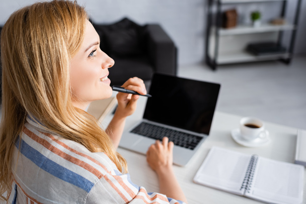 Enfoque selectivo de la mujer sonriendo mientras trabaja con el ordenador portátil
 - Foto, Imagen