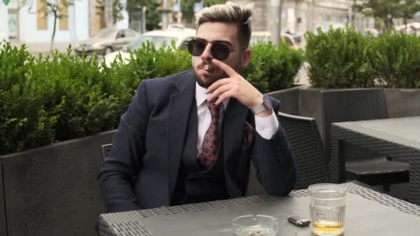 Серьезный бизнесмен курит сигары и пьет скотч или виски на террасе ресторана, элитный мужской клуб на открытом воздухе. отдых время
 - Кадры, видео