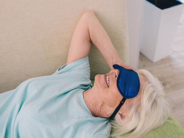 elderly (old) cheerful caucasian stylish woman with gray hair laying in sleep mask at home. Anti age, healthy lifestyle, positive thinking concept - Fotó, kép
