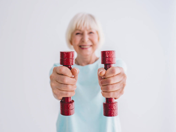 Senior fröhliche Frau beim Sport mit Hanteln. Anti-Alter, Sport, gesunder Lebensstil  - Foto, Bild