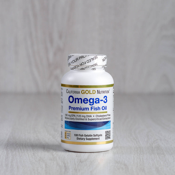 Kamyanets-Podilskyi, Ucrania - 27 de junio de 2020: California Gold Nutrition, Omega-3, Premium Fish Oil. Frasco con pastillas sobre un fondo de madera claro
. - Foto, Imagen