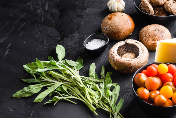 Portabello champignons ingrediënten voor bakken, cheddar kaas en salie op zwarte achtergrond. Zijaanzicht. - Foto, afbeelding