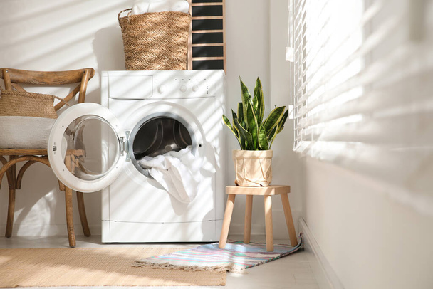 Modern washing machine in laundry room interior - 写真・画像