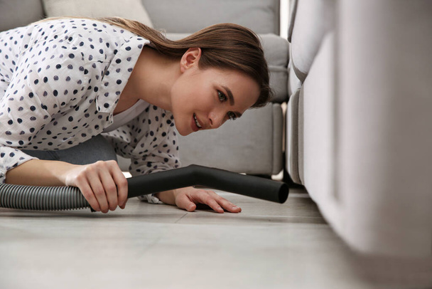 Young woman using vacuum cleaner at home - Foto, imagen