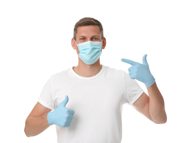 Male volunteer in mask and gloves on white background. Protective measures during coronavirus quarantine - Фото, зображення