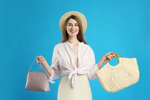 Beautiful young woman with stylish bags on light blue background - Photo, Image