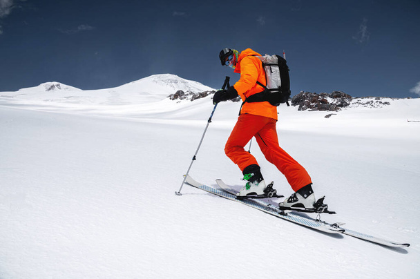 A skier in an orange suit skis in a mountain off-piste skiing in the northern caucasus of Mount Elbrus - Photo, Image