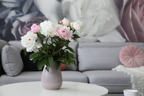 Bouquet of peonies on table near sofa in modern room. Interior design - Fotoğraf, Görsel