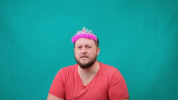Giocoso uomo barbuto strambo in una t-shirt rosa con un deadema sulla testa triste con una bacchetta magica in mano. Uno scherzo divertente mago per fare e soddisfare un desiderio. - Filmati, video