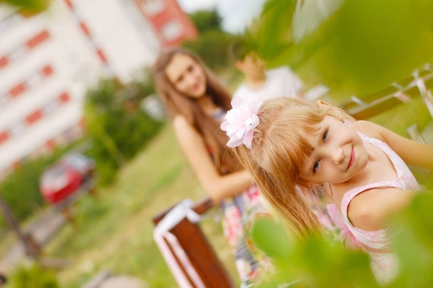 Mladá dívka chodí do parku se svou starší sestrou a bratrem. Má legrační obličej. - Fotografie, Obrázek