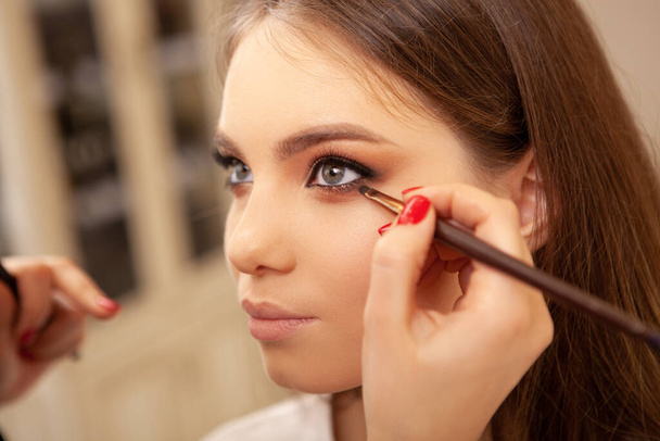 Beautiful sexy young female model getting professional makeup before fashion show - Foto, afbeelding