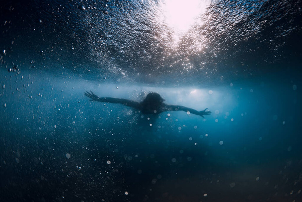 海の波の下でサーフボードなしで女性ダイビング。波と砂の底の下に潜る水中アヒル - 写真・画像