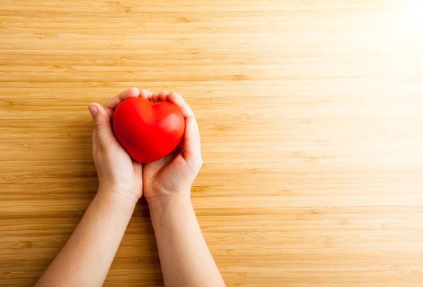 Zdravotní péče, darovat, medicína a charitativní koncept - zblízka dětské ruce drží červené srdce - Fotografie, Obrázek