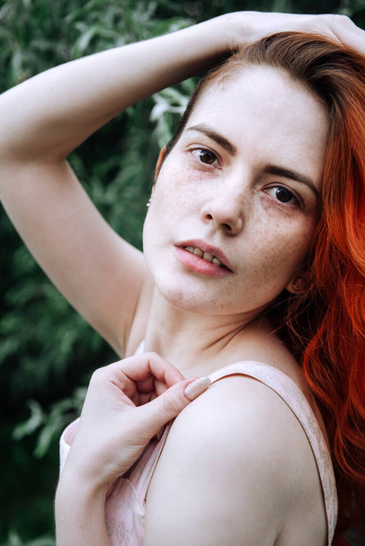 portrait of 1 young white woman with red hair and freckles, face of a European beautiful girl against a background of greenery - Foto, afbeelding