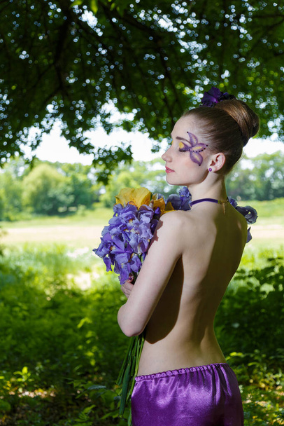 Ritratto di una ragazza con schiena nuda e fantasia creativa make-up con bouquet di fiori di iris - Foto, immagini