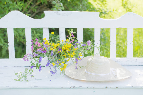 wild flowers on white wooden bench in summer garden - Фото, зображення