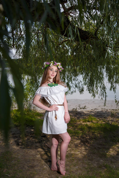 Menina bonita em vestido branco e flores grinalda no fundo do salgueiro verde. 7 de julho, tradicional feriado eslavo com rituais de adivinhação e adivinhação na Ucrânia
. - Foto, Imagem