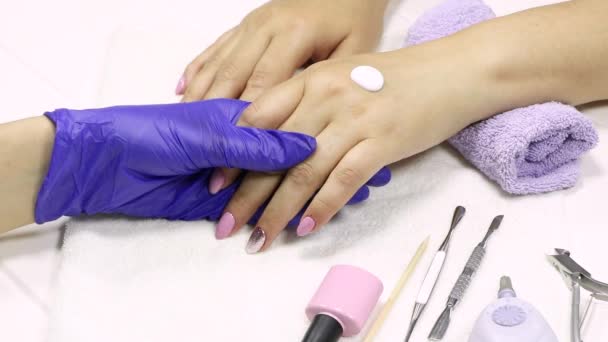 The manicurist applies a moisturizer to the client's hand. SPA manicure, procedure, moisturizing. Hand lotion, cream. Skin care. Beauty salon. Manicure concept. Beauty nails. Soft skin. Cosmetic cream - Footage, Video